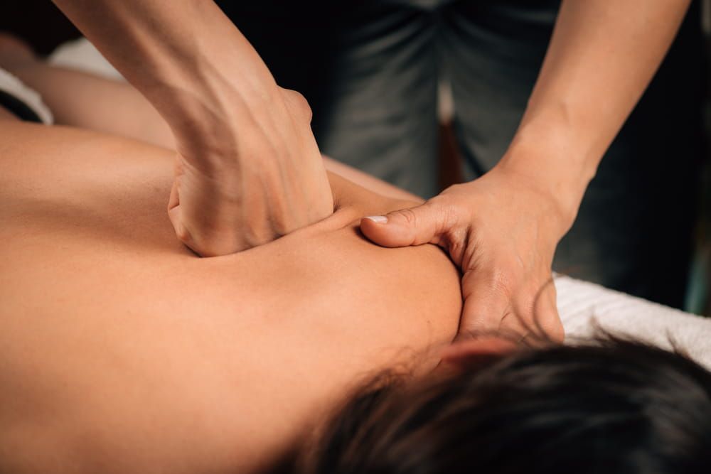 Therapist applying firm pressure to a client's shoulder during deep tissue massage therapy