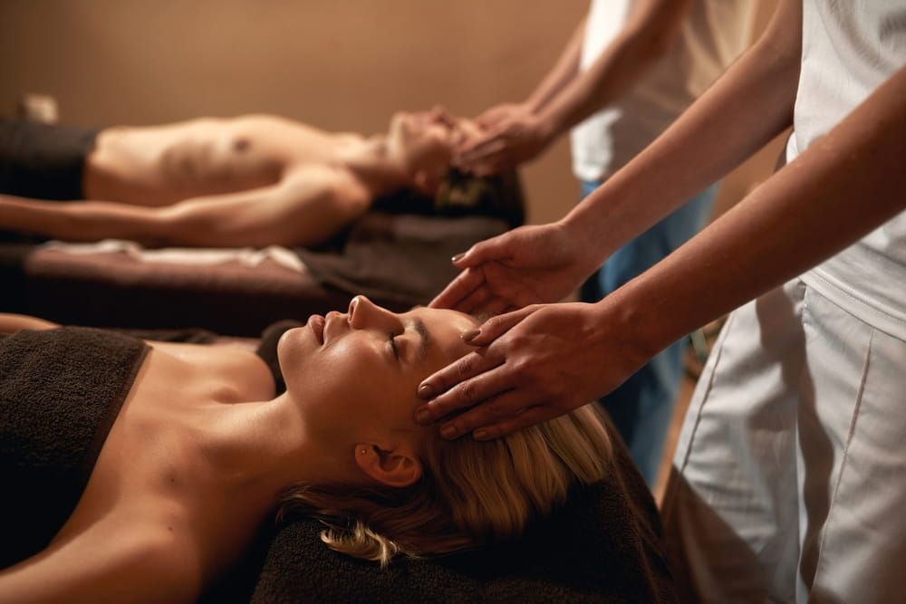 A couple enjoying a romantic couple massage side by side in a private spa room