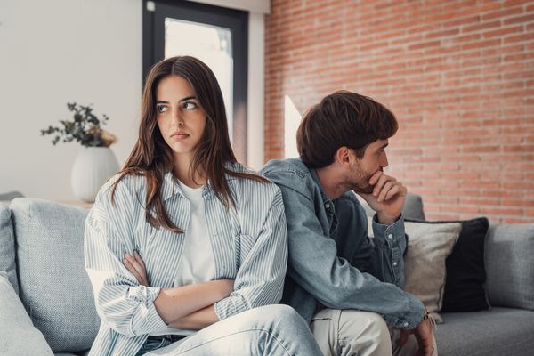 Couple sitting apart on couch showing signs of relationship burnout and emotional distance