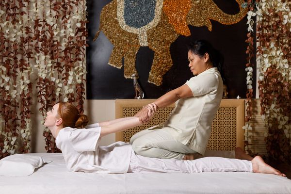 A woman receiving a traditional Thai massage with assisted stretching from a licensed therapist