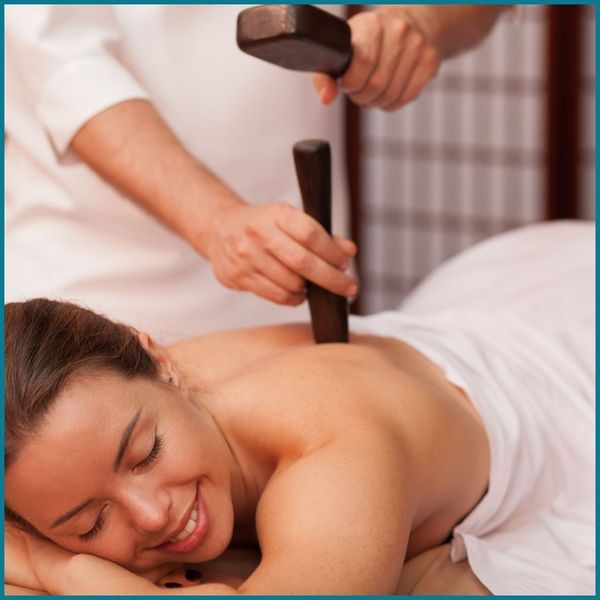 woman having tool used to apply pressure to back during massage