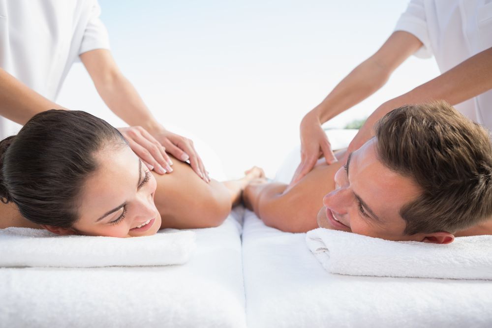 couple receiving a couple’s massage share a look during their treatment