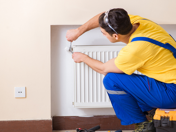 Young repairman contractor repairing heating panel. Young repairman contractor repairing heating panel.