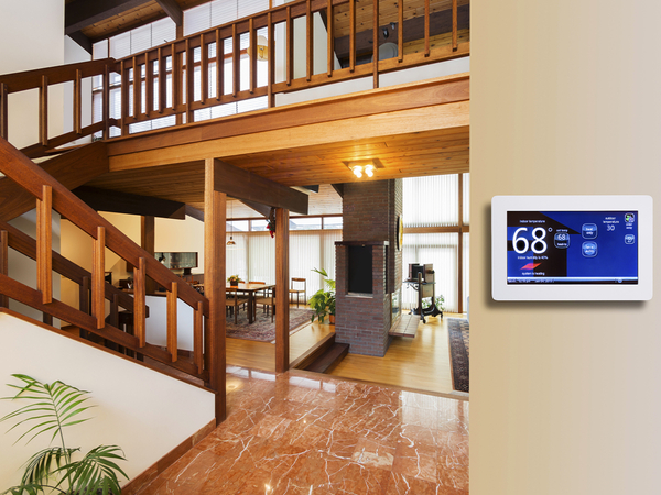 Programmable electronic thermostat on beige wall in house entrance way. Programmable electronic thermostat on beige wall in house entrance way.