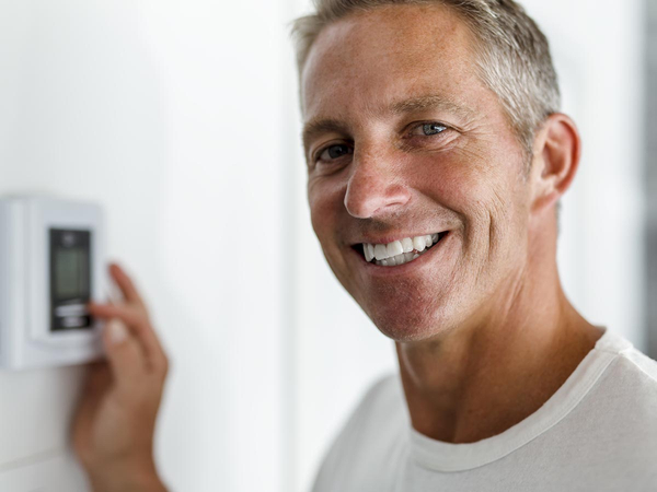 Smiling man adjusting thermostat