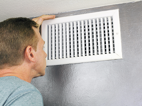  Man looks at his home’s air duct vent.