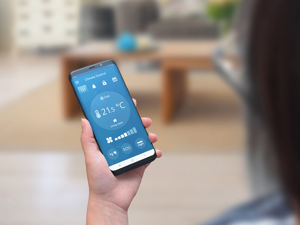 Woman use climate control app on a phone in the living room to adjust temperature and ventilation. Woman use climate control app on a phone in the living room to adjust temperature and ventilation.
