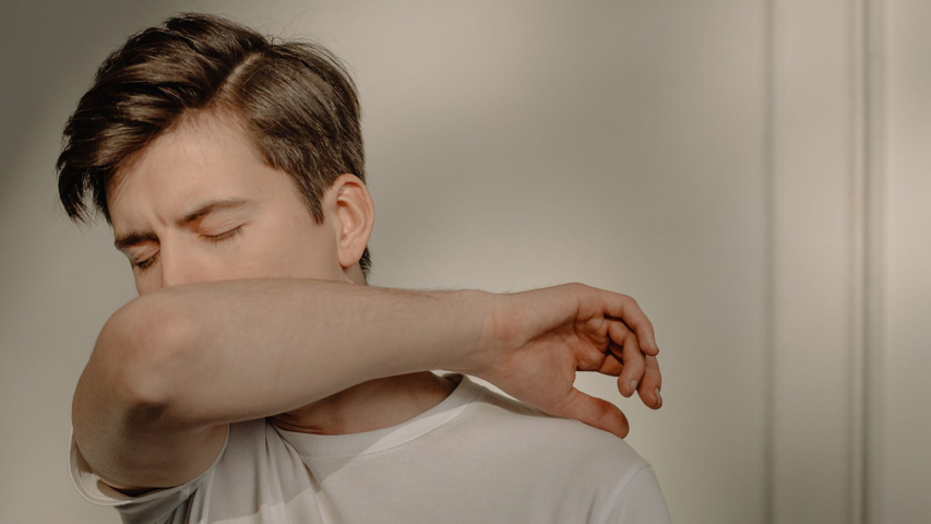 man coughs into elbow
