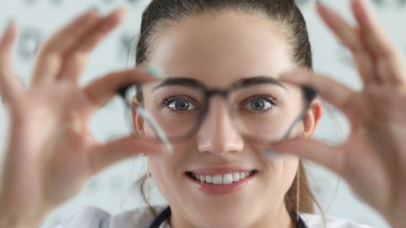 Woman holding eye glasses up to her eyes. 