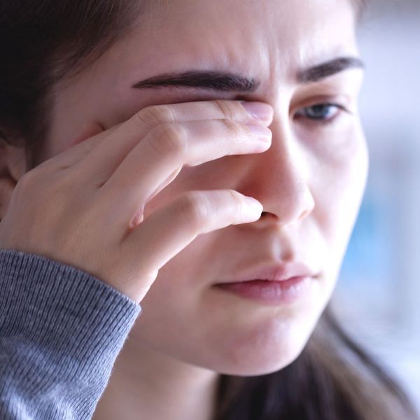Woman itching her eyeball and looking distressed. 