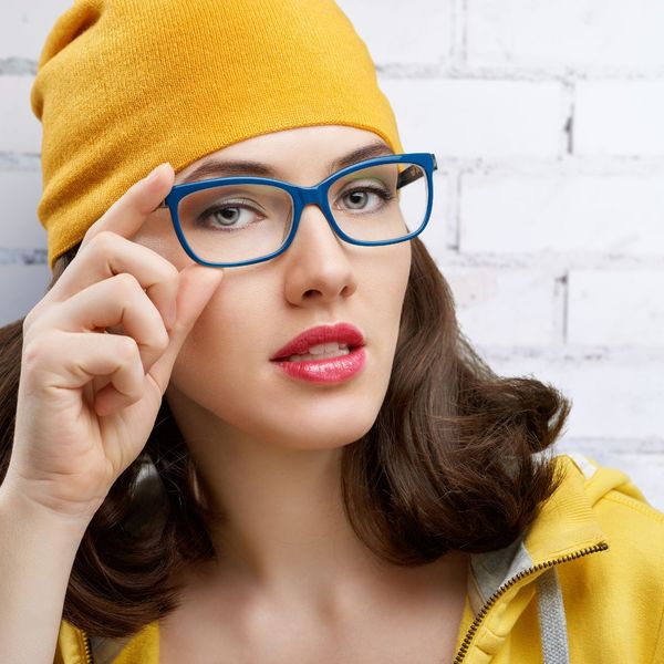 woman in yellow putting on glasses