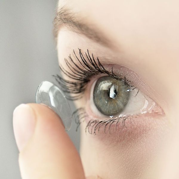 Person putting a contact lense in their eye. 