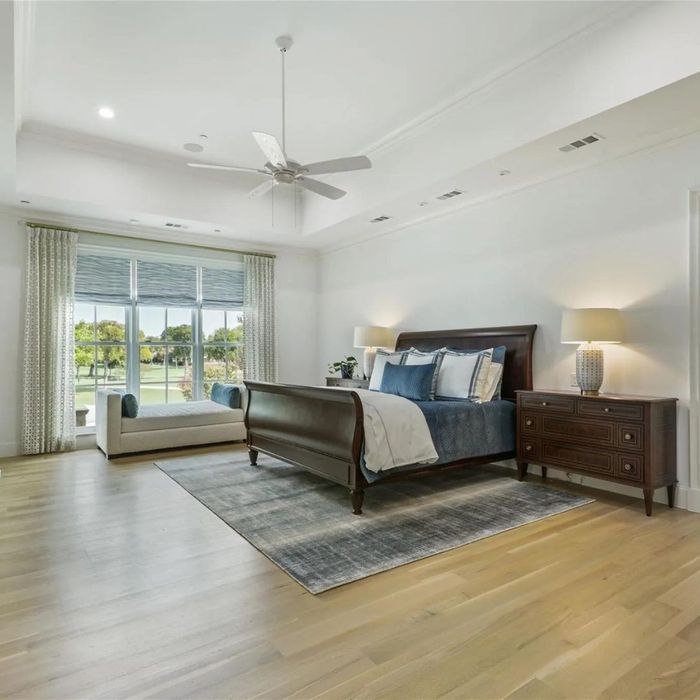 a grey and white bed in a large bedroom