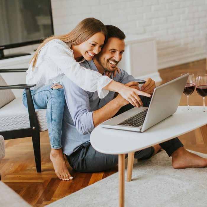 Cheerful Couple Searching Internet on Laptop at Home