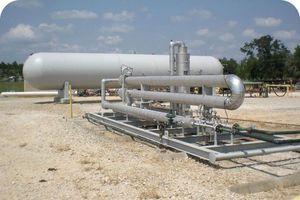 A JT skid unit with pipes and valves, next to a large NGL storage tank at a gas processing site.