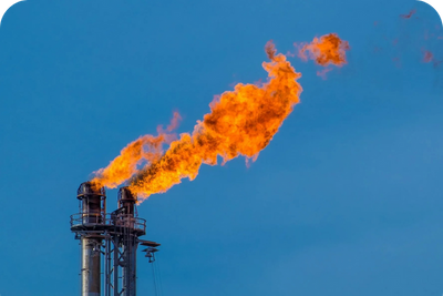 A natural gas flare stack burning off excess gas with a bright orange flame.