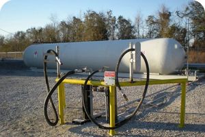 A large NGL processing bullet tank with a loading station and hoses in the foreground.