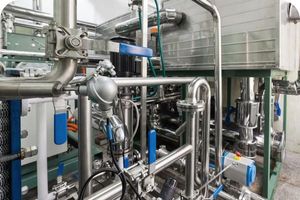 A detailed view of the complex, interconnected stainless steel pipes and valves of a gas refrigeration plant.