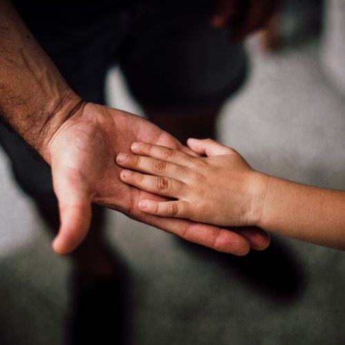 Hand of a small child inside the hand of a man