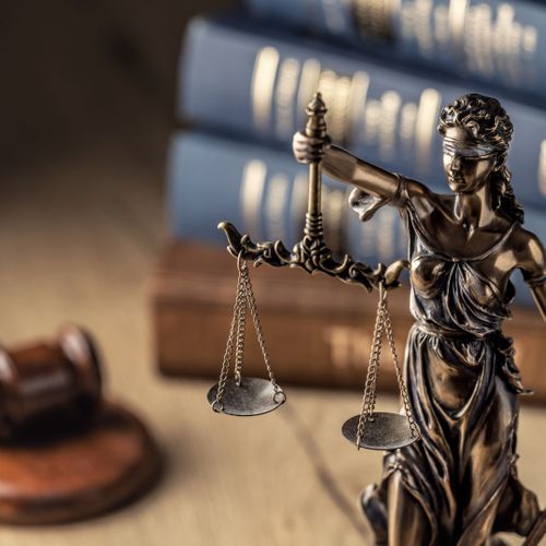 Justice scale in front of a gavel and law books