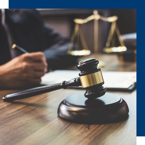 a gavel on a table with a person looking at paperwork