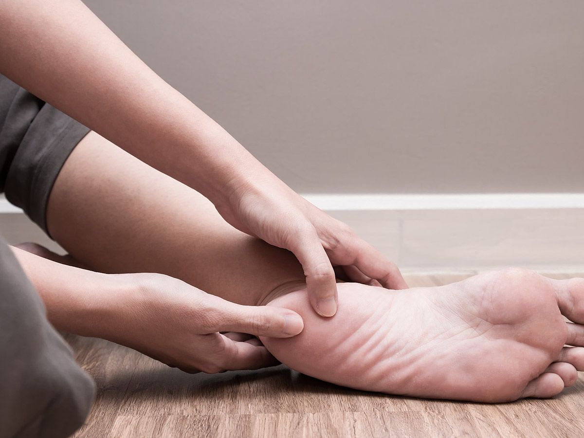 Person holding the heel of their foot while in pain
