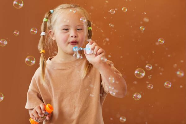 child with down's syndrome blowing bubbles