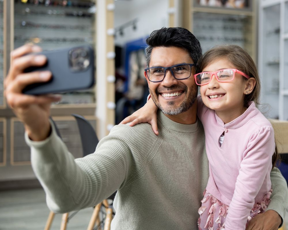 Father and daughter in new glasses taking selfie