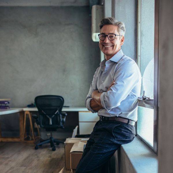 smiling business man leaning against window