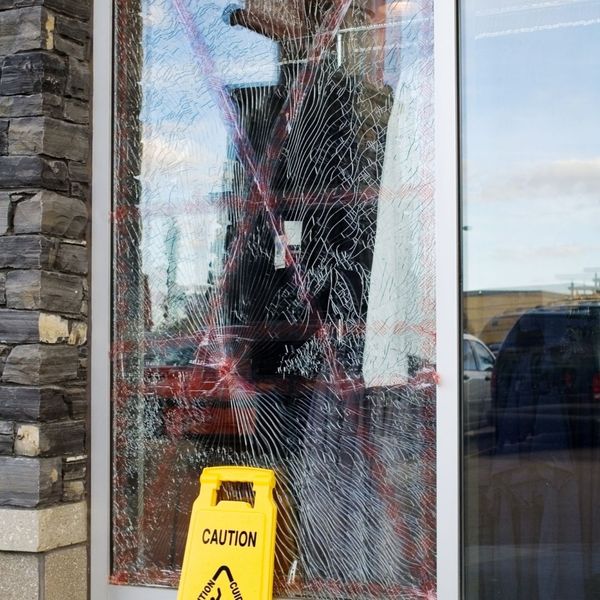 broken storefront window with caution sign