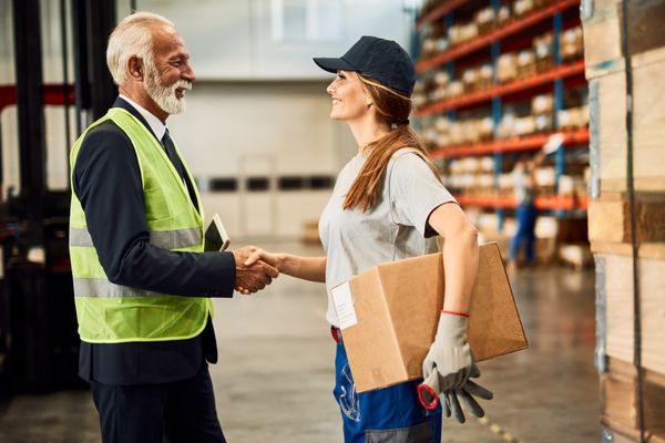 happy-female-warehouse-worker-handshaking-with-company-manager-industrial-storage-compartment.jpg