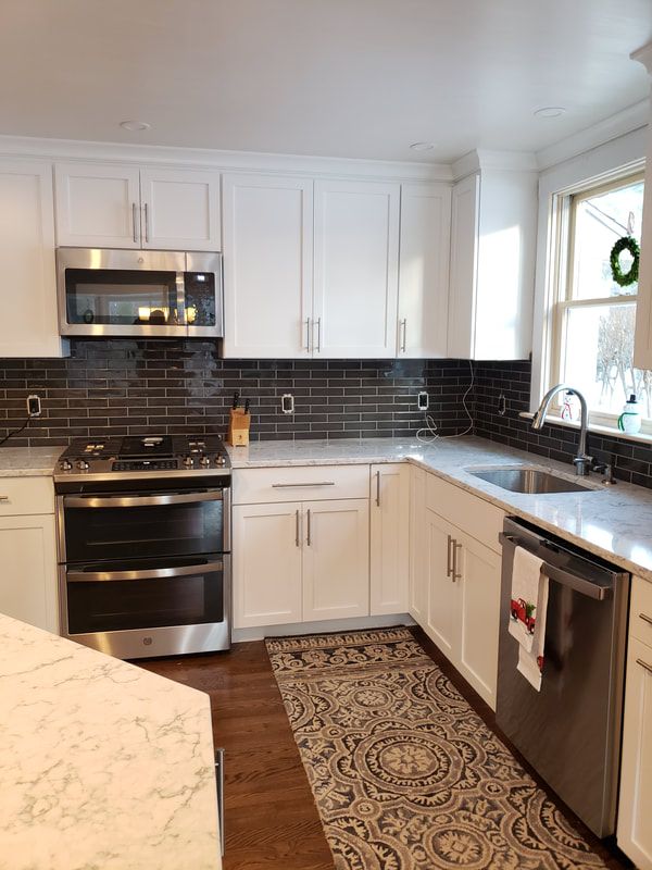 kitchen-remodel-after-marble-counters-black-backsplash-white-cabinet_1.jpg