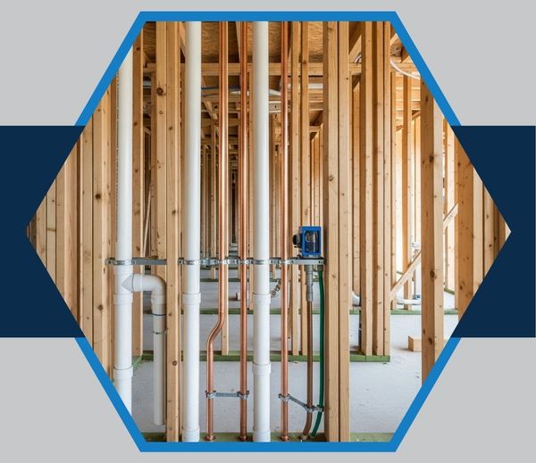 Neatly installed copper and PVC pipes within the wooden frame of a new construction project, showcasing expert new plumbing construction.