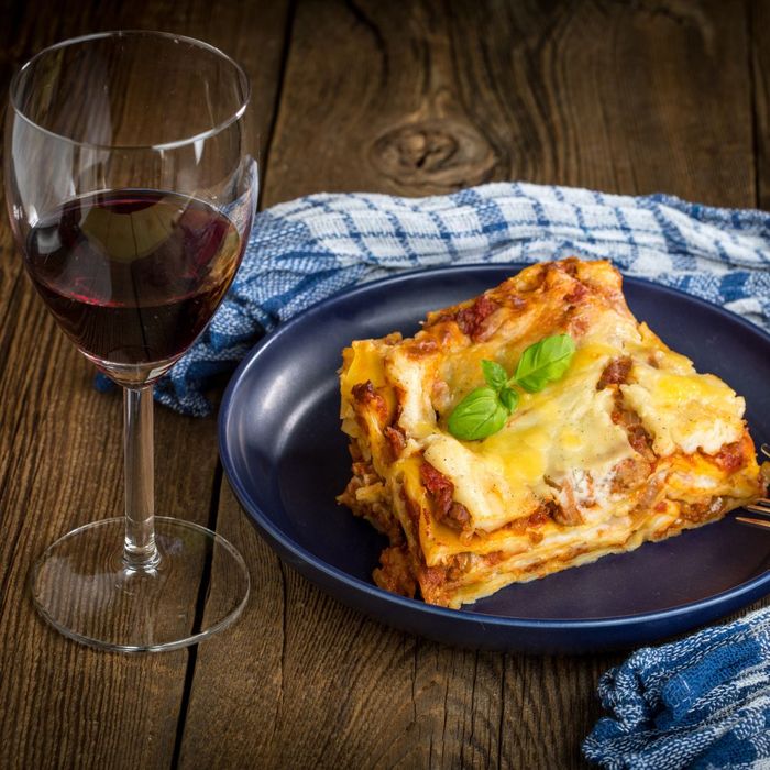 a plate with meat lasagna and red wine