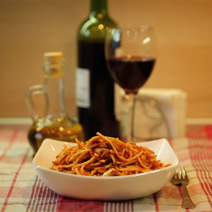 a bowl of spaghetti with red sauce and red wine