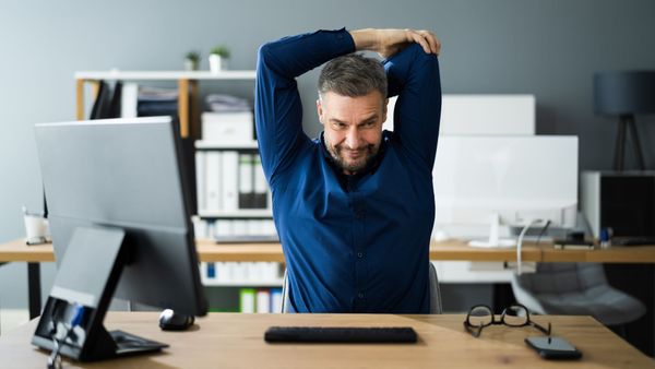 worker stretching shoulders at desk