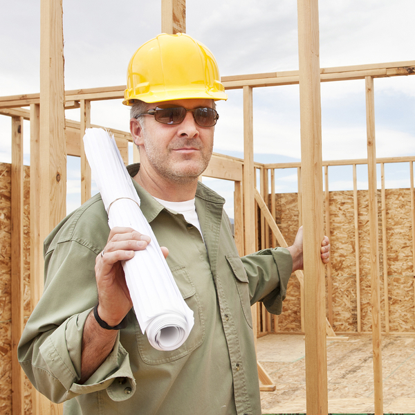 Image of a builder next to a house frame