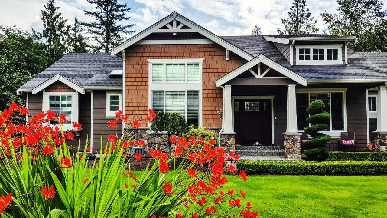 small gray and brown home with a bright green lawn