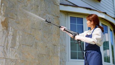 a woman power washing a home's exterior a woman power washing a home's exterior