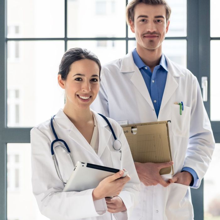 Male and a female doctor holding files, smiling. 