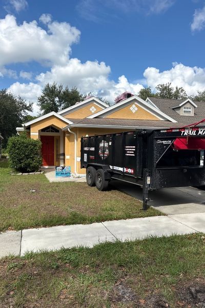 A home with a Patriot Dump and Haul dumpster parked in the driveway.