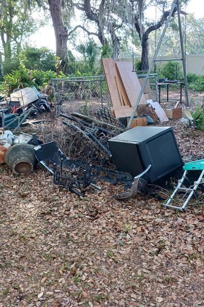 A pile of "junk", including old pots, appliances, and more, in a yard.