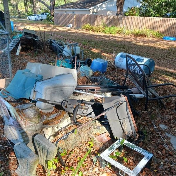 A pile of "junk", including a vacuum, chair, and other items, in a home's yard.