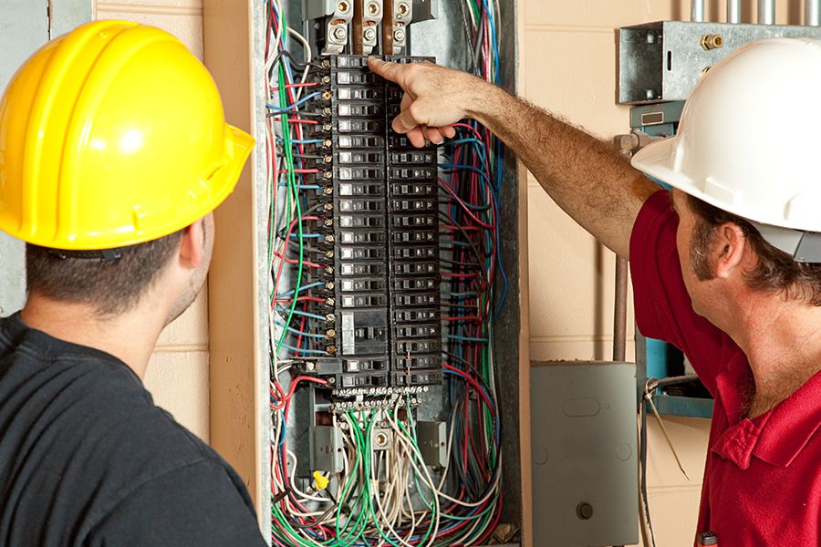 Two electricians looking at a circuit breaker