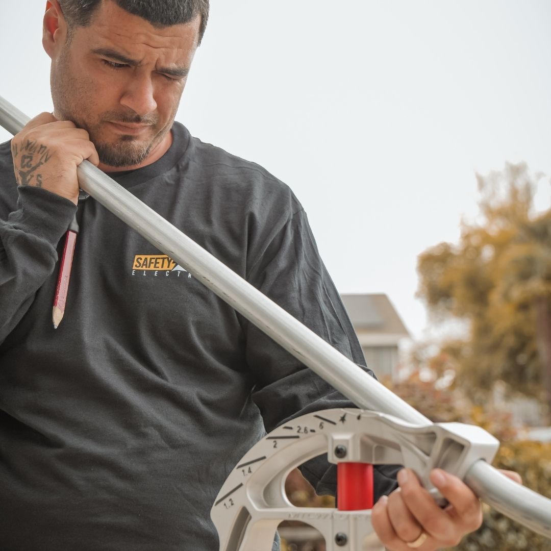 An electrician bending a metal electrical conduit outdoors