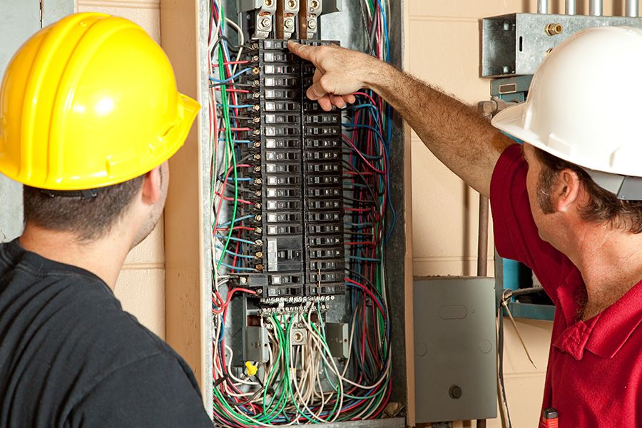 two electricians discuss on a electric panel