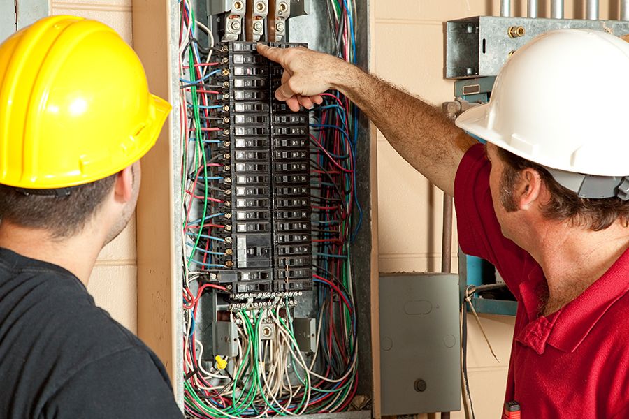 Two electricians working on a fuse box