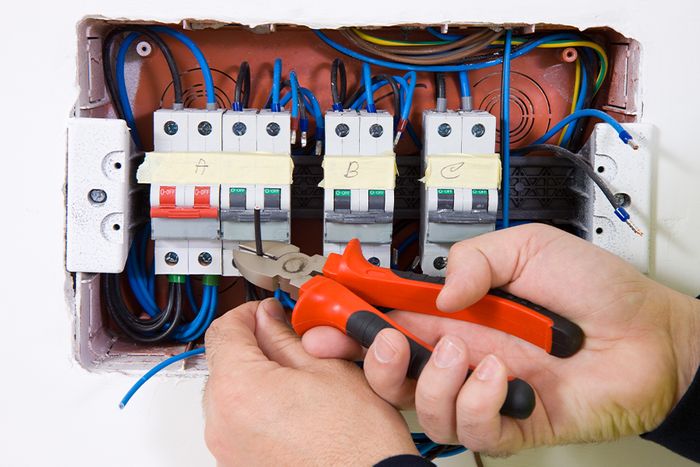An electrician working on a fuse box