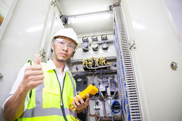 electrical engineer giving thumbs up by panel