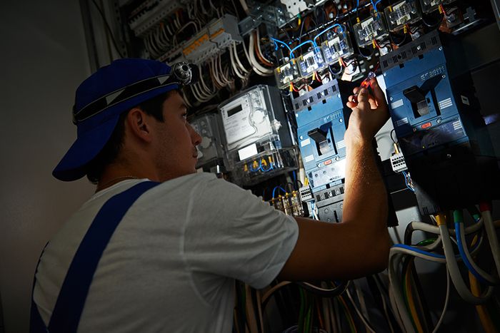 Electrician with a flashlight trying to repair a power outage